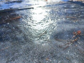 Sunlight shining on ice on asphalt. Ice slick on the road in the city. Cold, frosty weather. Winter morning. Background for text.