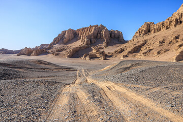 Desert road and Yardang landform mountain natural landscape under blue sky. Road trip in no man's land.