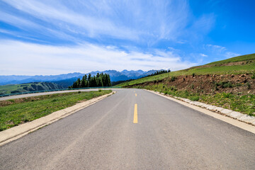 Countryside asphalt road and green meadow with mountains nature landscape on a sunny day. Road trip.