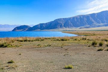 Gravel road ground and blue lake natural landscape. Beautiful Sayram Lake natural scenery in...