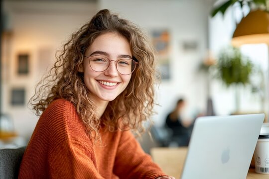 Young Woman Studying Online with Laptop in Bright Modern Room Casual Attire Smiling Working from Home