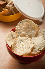 Fried Indonesian snack, in red bowl with yellow container in background