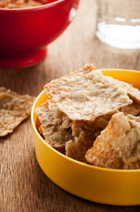 Crispy fried tempeh chips served in yellow bowl with dipping sauce