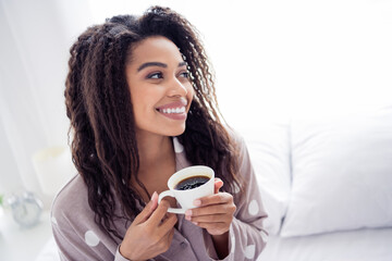 Young afro-american woman enjoying morning coffee in natural daylight wearing cozy sleepwear