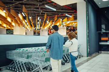 Couple taking shopping cart entering grocery store together