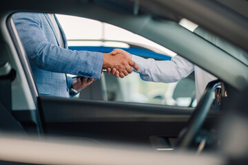 Handshaking and exchange of car keys, symbolizing conclusion of deal.