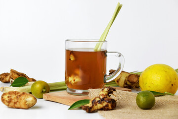 Closeup photo of hot red ginger drink in a glass cup with some raw ginger