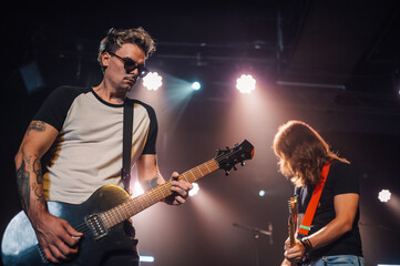 Obraz premium Guitarists playing electric guitars on stage during concert