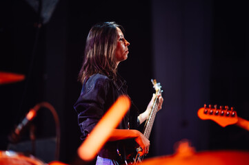 Female musician playing bass guitar on stage during live performance