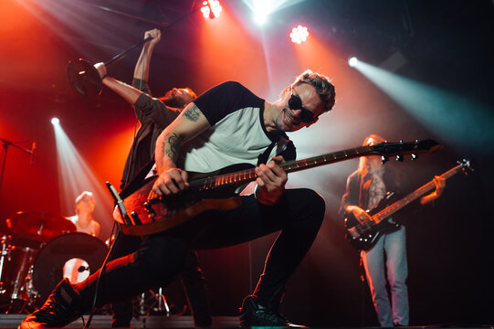 Guitarist performing live on stage with bandmates - Powered by Adobe