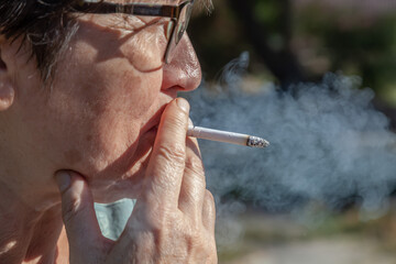 Senior woman smoking cigarette close up