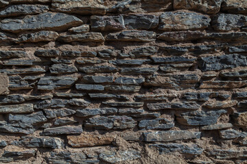 Old ruined masonry made of gray natural stone of different sizes and shapes. Background for design.