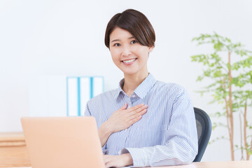 パソコンで仕事する胸に手を当てる女性