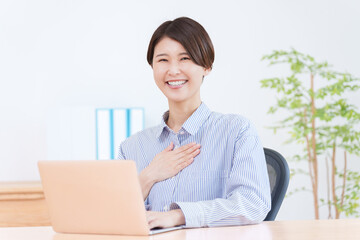 パソコンで仕事する胸に手を当てる女性