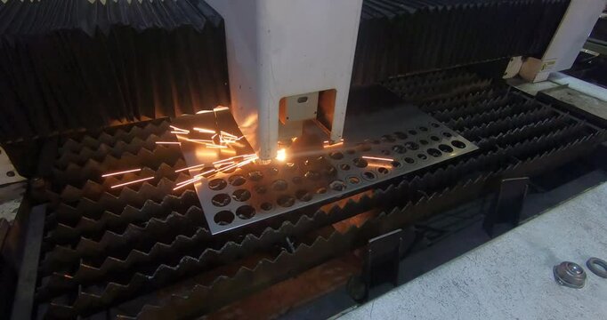 An industrial laser, following a predetermined trajectory, cuts holes in sheet metal