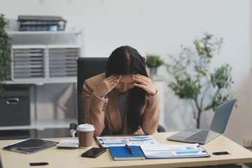 Portrait of tired young business Asian woman work with documents tax laptop computer in office....