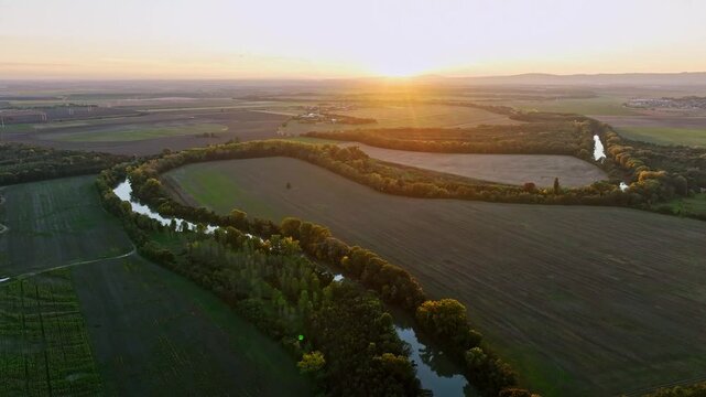 Drone Panorama of Small Danube river from drone at sunset with gren fields and sun, Slovakia