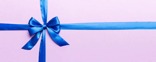 Top view of blue ribbon rolled and blue bow isolated on colored background. Flat lay with copy space