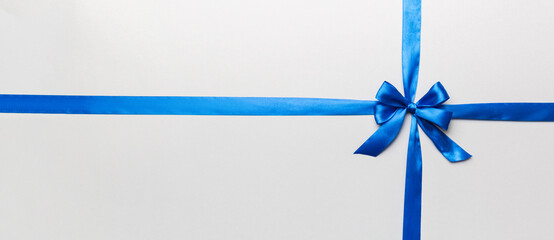 Top view of blue ribbon rolled and blue bow isolated on colored background. Flat lay with copy space