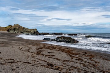 Rocky coastline with crashing waves and sandy beach.