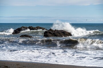 Waves crashing against rocks on a sunny beach.
