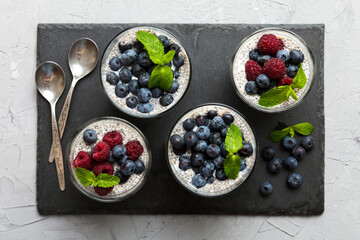 Healthy breakfast or morning with chia seeds vanilla pudding raspberry and blueberry berries on table background, vegetarian food, diet and health concept. Chia pudding with raspberry and blueberry