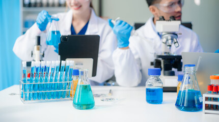 Scientists in lab coats collaborating with test tubes, flasks, and microscopes in a modern lab.