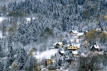 Single-family houses on the snow-covered hill amidst winter forests