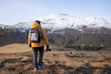 Persona de viaje Hombre de espaldas de viaje en Islandia con cámara de fotos con montañas...