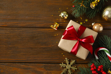 Beautiful gift box tied with bow Christmas decorations, confetti on wooden background 