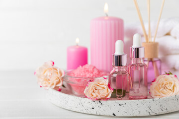 Rose essential oil on a textured background.Roses and a bottle of rose perfumed water.Aromatherapy treatment. Beauty concept. Spa procedure.Natural organic oil.Anti-stress,detox relax.Place for text