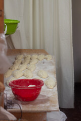 Vertical photo. Soft selective focus. Raw buns and wheat white flour on bakery table. Dough for baking. Process of cooking grandma food, sweets, buns with jam, potato, meat, cabbage. Tbilisi. Georgia