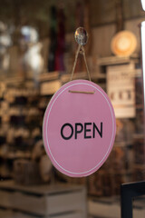 Vertical street photo. Round pink sign with text Open on glass door of store of cosmetics, gifts. Concept of Black Friday, online shopping, gift, mega discount, cyber monday offer, 11 november. Day