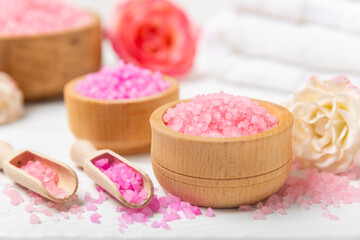 Sea salt for bath with aroma and rose flowers on textured wooden background. Pink sea salt. Spa treatments. Natural salt with herbs and essential oils. skincare concept. Meso for text. Copy space