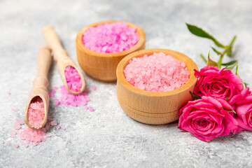 Sea salt for bath with aroma and rose flowers on textured wooden background. Pink sea salt. Spa treatments. Natural salt with herbs and essential oils. skincare concept. Meso for text. Copy space