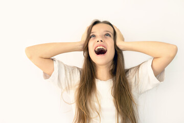 A young beautiful girl screams and holds her head. Happiness and joy, happy cry, winner