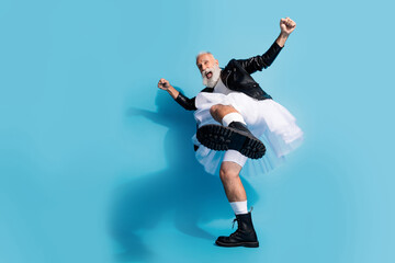 Photo of funky extravagant senior transgender man dancing raise feet boots core wear female clothes isolated blue color background