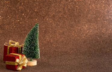 Christmas gifts in red with a ribbon and a Christmas tree on a brown shiny background. Place for text, New Year 2025