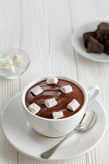 hot melted chocolate with marshmallows in cup on white wooden table