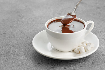 hot chocolate with marshmallows in cup and in spoon on table