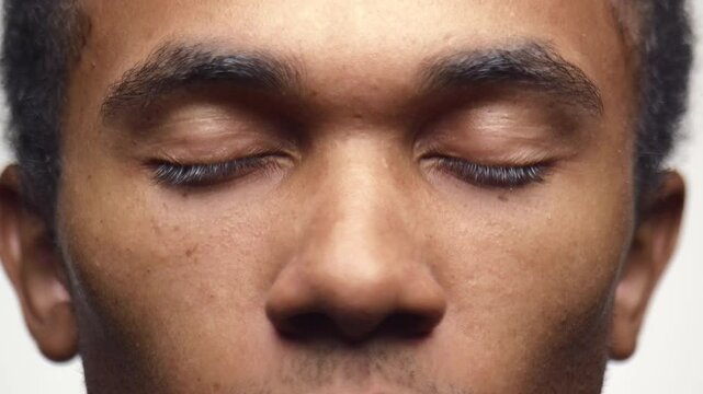 Close-up of young man slowly closing his eyes in calm focus
