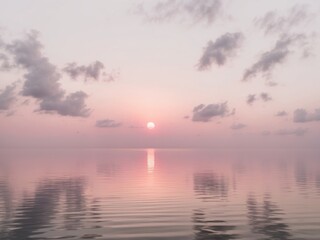 Naklejka premium Serene pink sunrise tranquil lake with reflective water.
