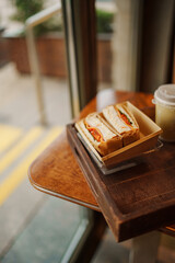 A box with a sandwich on a table in a coffee shop on a tray with a cup of coffee.