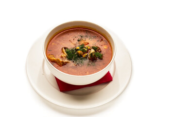 A bowl of soup with a red napkin on top of a white plate