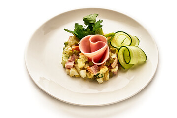 A plate of food with a ham and cucumber on it