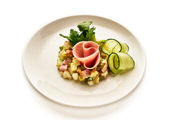 A plate of food with a ham and cucumber on it