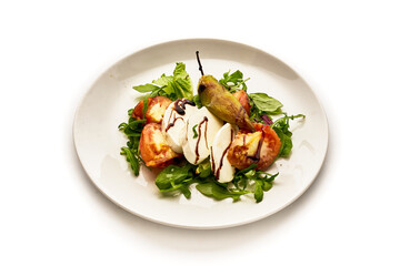 A white plate with a salad of tomatoes, cucumbers, and basil