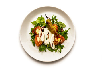 A white plate with a salad of tomatoes, cucumbers, and basil