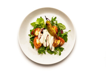 A white plate with a salad of tomatoes, cucumbers, and basil