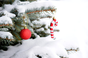 a red and white christmas candy and ornament hangs on a christmas tree with snow